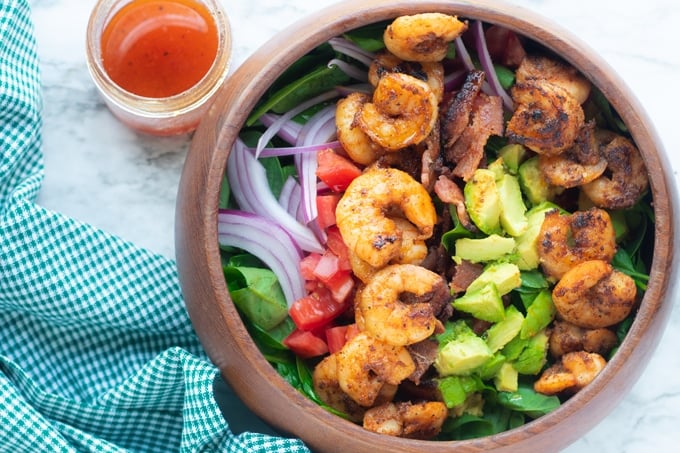 shrimp spinach salad recipe in a bowl with vinaigrette on the side