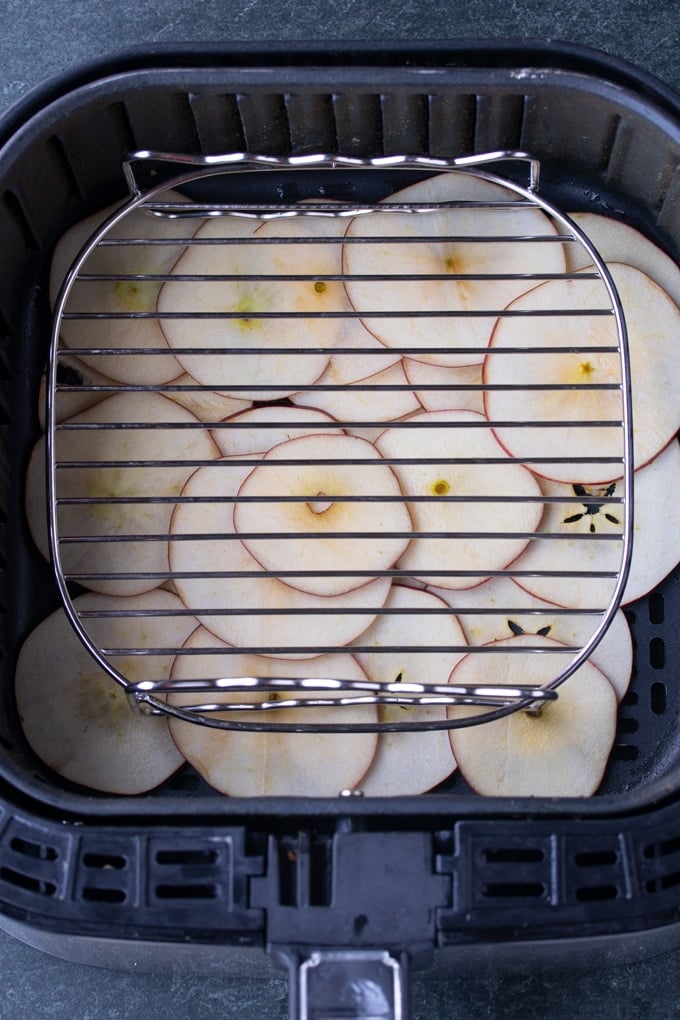 sliced apples in air fryer basket under rack