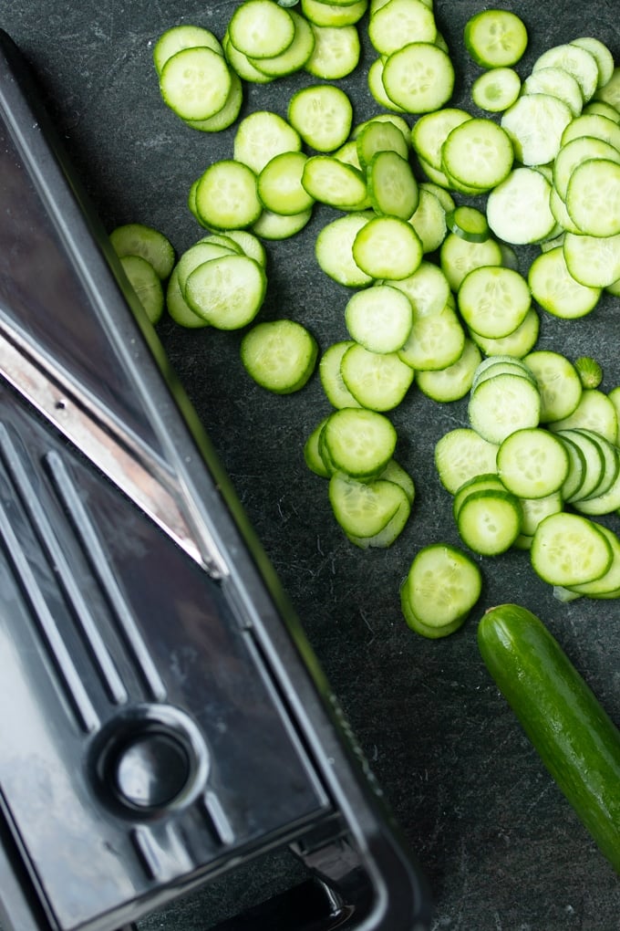 sliced cucumbers next to mandolin