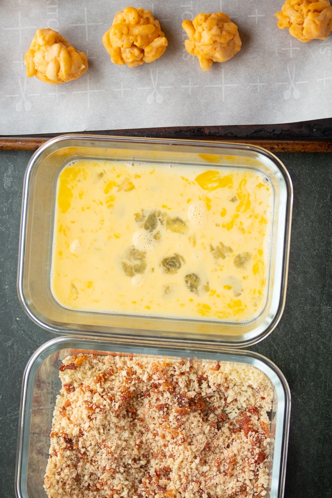 dredgins station of eggs, panko, and macaroni and cheese balls in front of air fryer basket