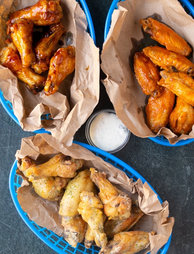cooked chicken wings in baskets with ranch in the middle