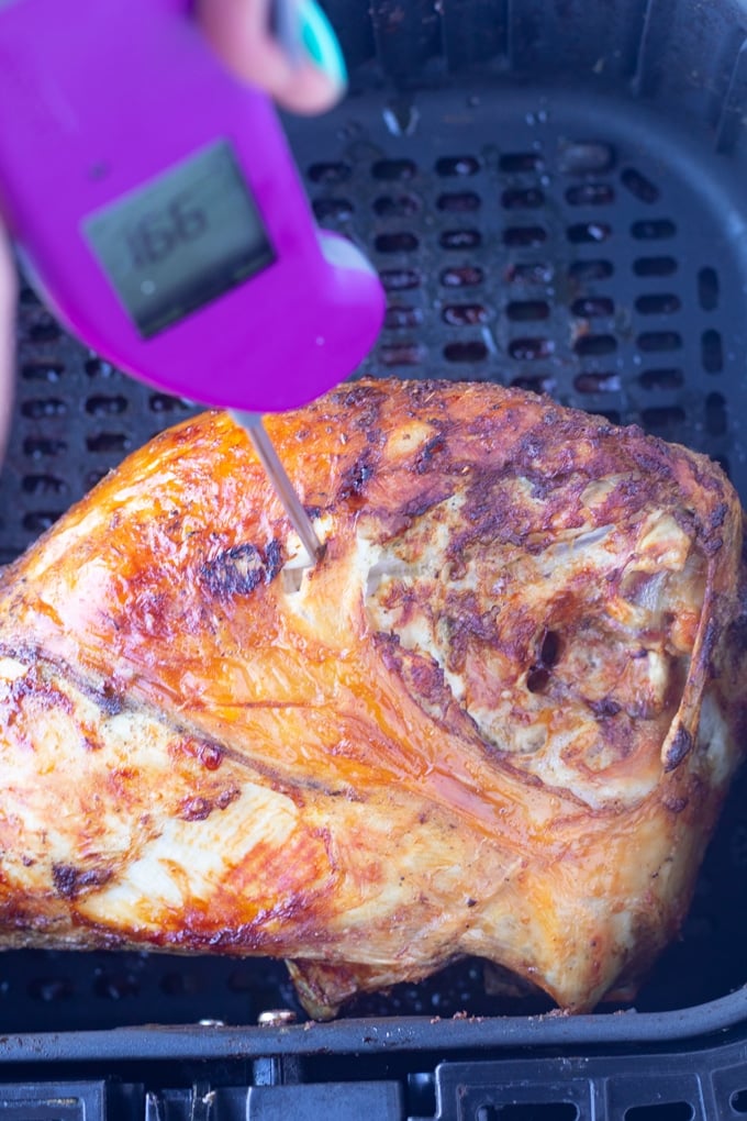 turkey breast in air fryer basket with thermometer testing meat