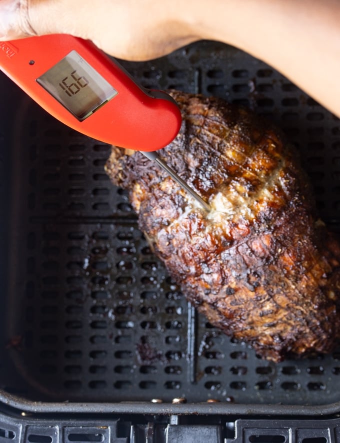 cooked turkey breast in air fryer basket with thermometer sticking out