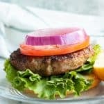 air fried turkey burger with lettuce, tomato, and onion on white plate