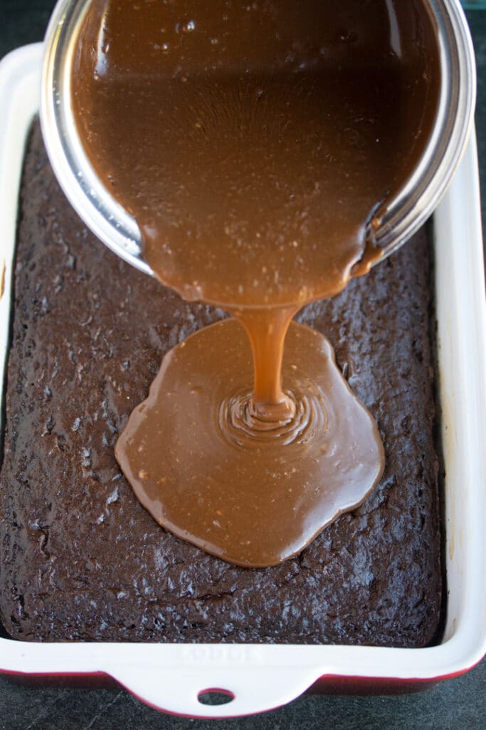 cola frosting being poured over chocolate cake