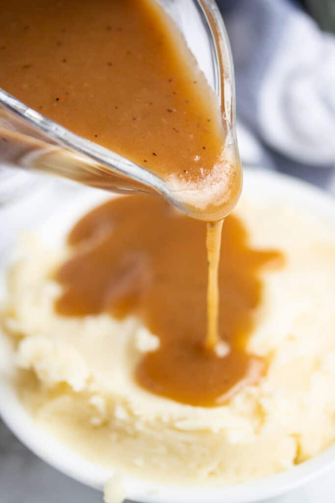 Gravy being poured onto mashed potatoes