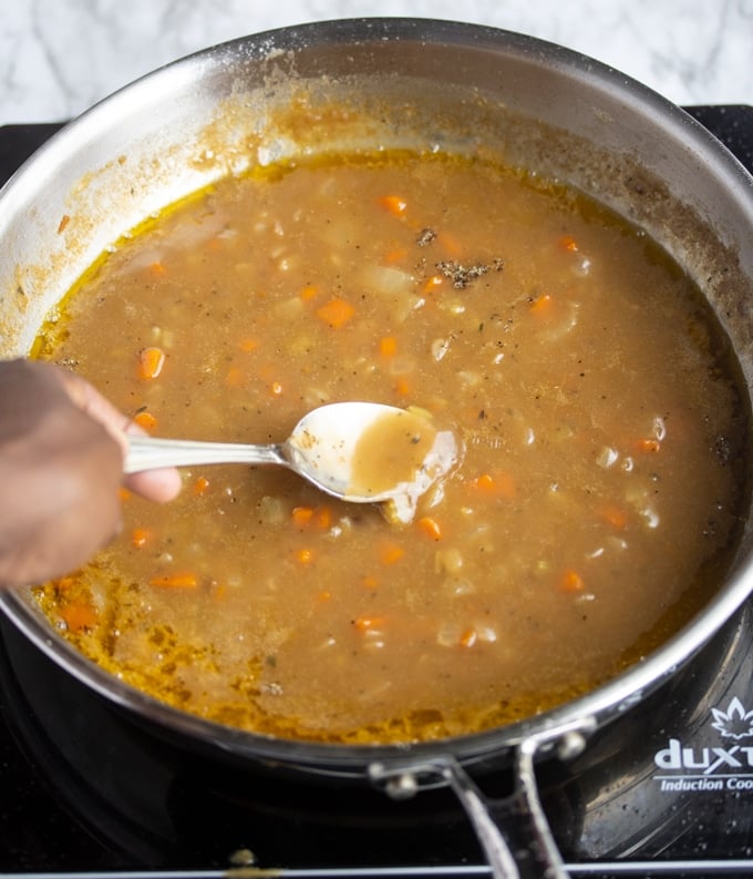 Gravy in skillet with spoon dipping into the middle