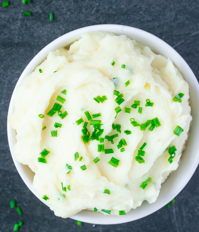 mashed potatoes covered in chives in white bowl