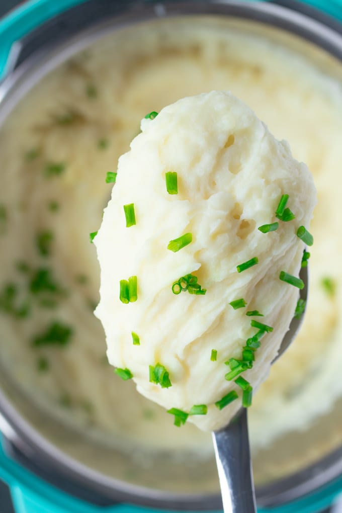 instant pot mashed potatoes on a spoon with chives on top