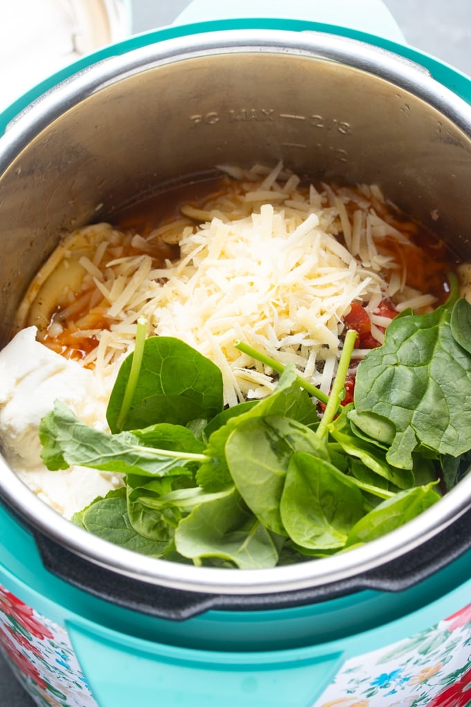 all ingredients inside the instant pot, cheese and spinach on top