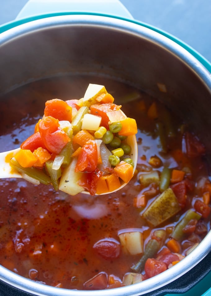 Vegetable soup on a ladle over Instant Pot filled with vegetable soup