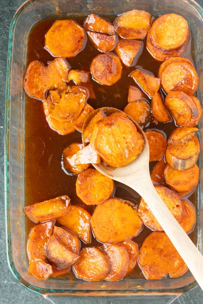 finished candied sweet potatoes with wooden spoon in pan