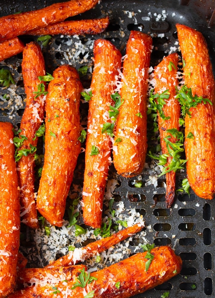 Savory air fryer carrots in air fryer basket topped with parmesan cheese and parsley