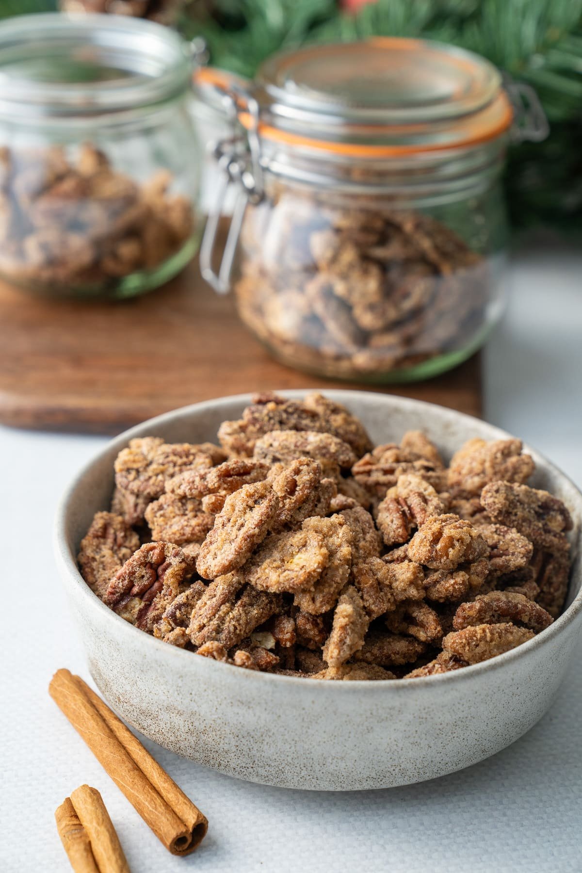 cinnamon sugared pecans in bowl with sugared pecans in jars in background