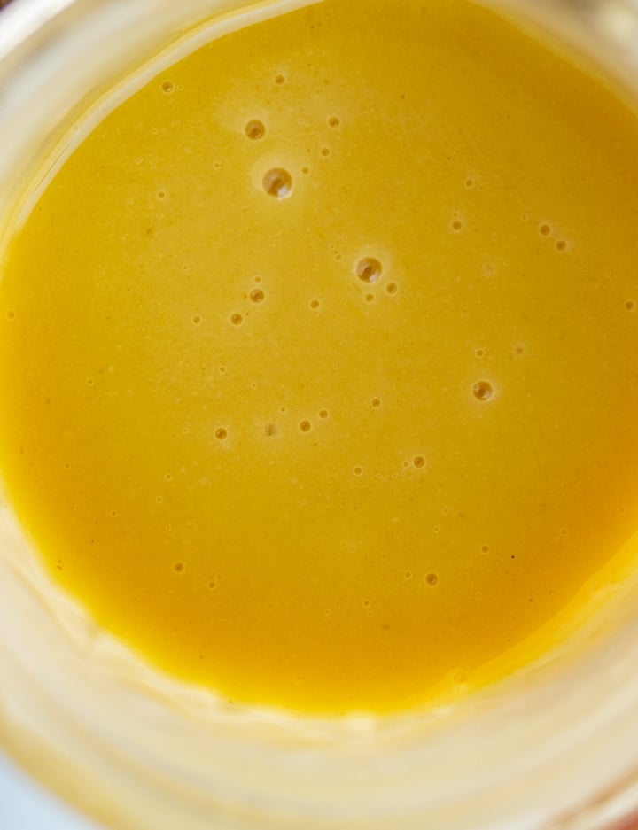 close up photo of yellow salad dressing in mason jar