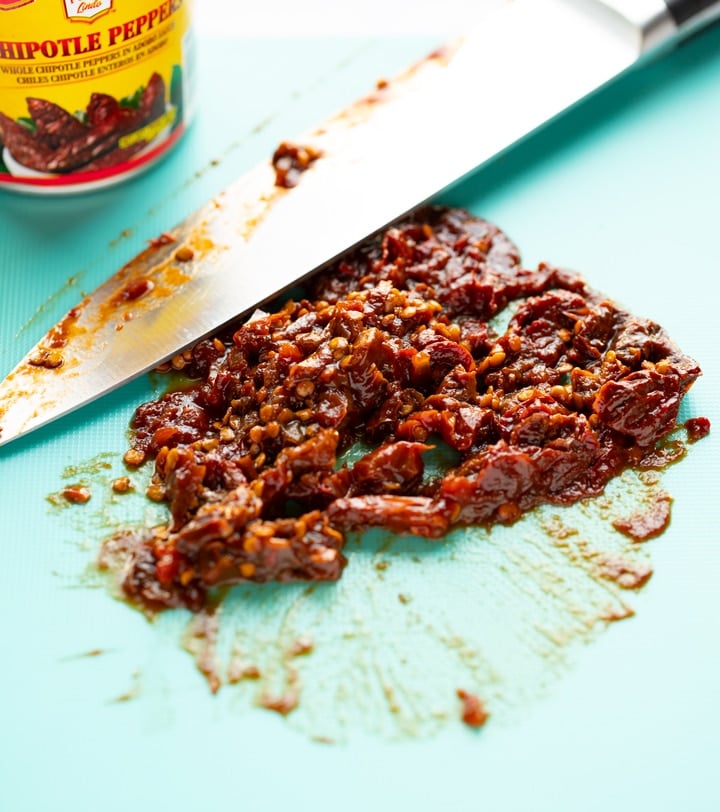 chipotle peppers chopped on cutting mat with knife laying next to it