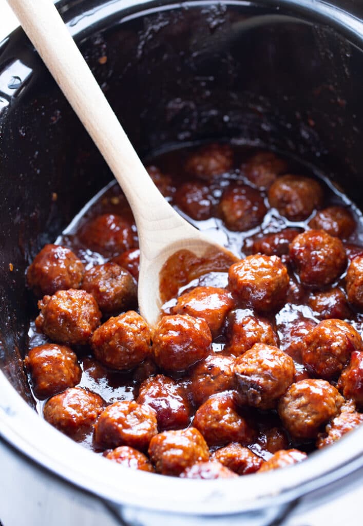 party meatballs in the slow cooker liner with wooden spoon sticking out