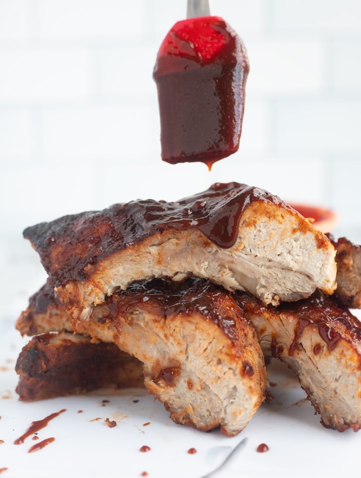 air fryer ribs stacked with bbq sauce dripping from brush