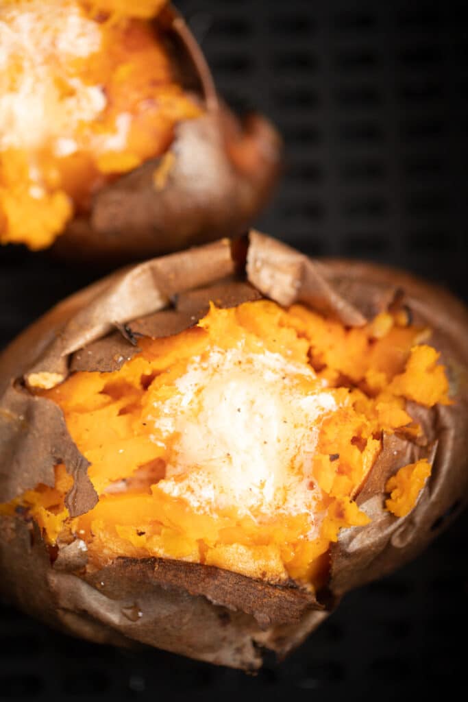 cook air fryer sweet potato in basket opened and topped with hot honey butter