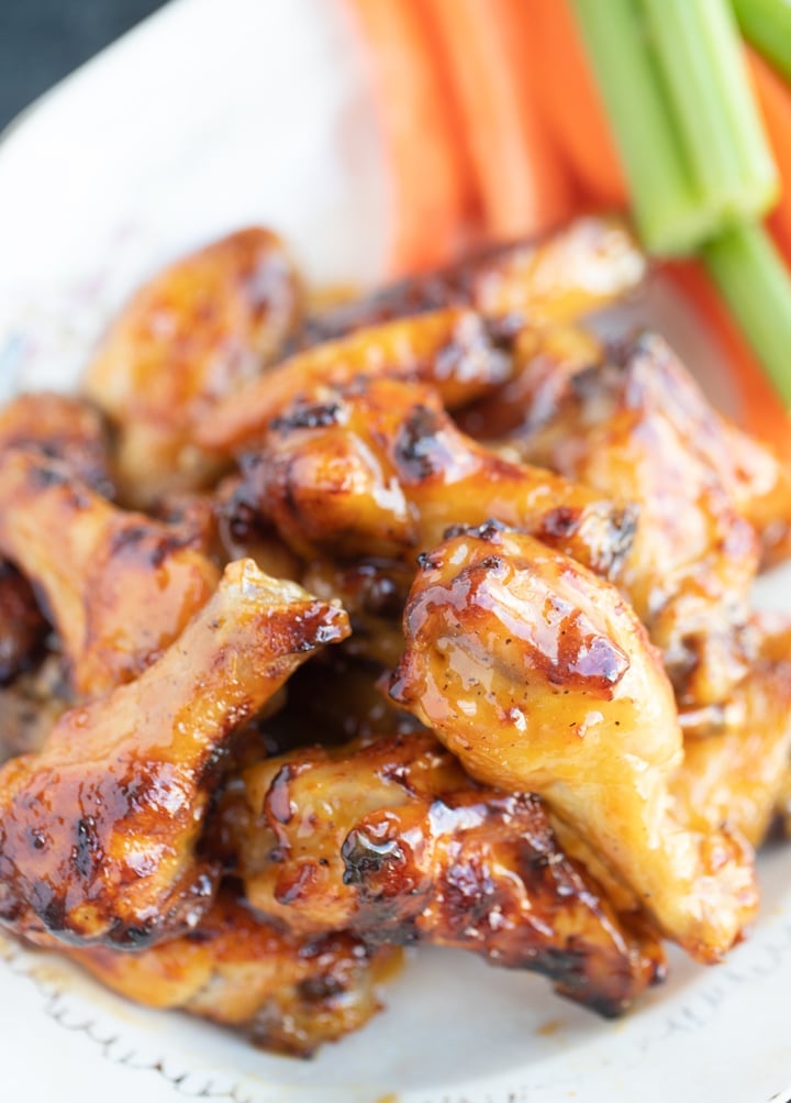 honey mustard wings on a plate with celery and carrots in the back