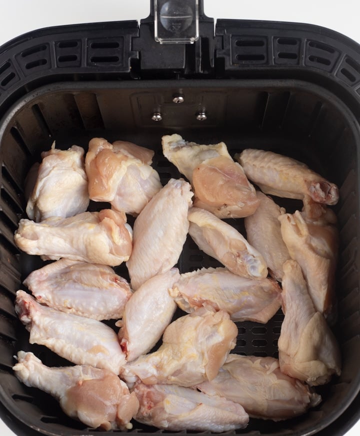 raw chicken wings in an air fryer basket