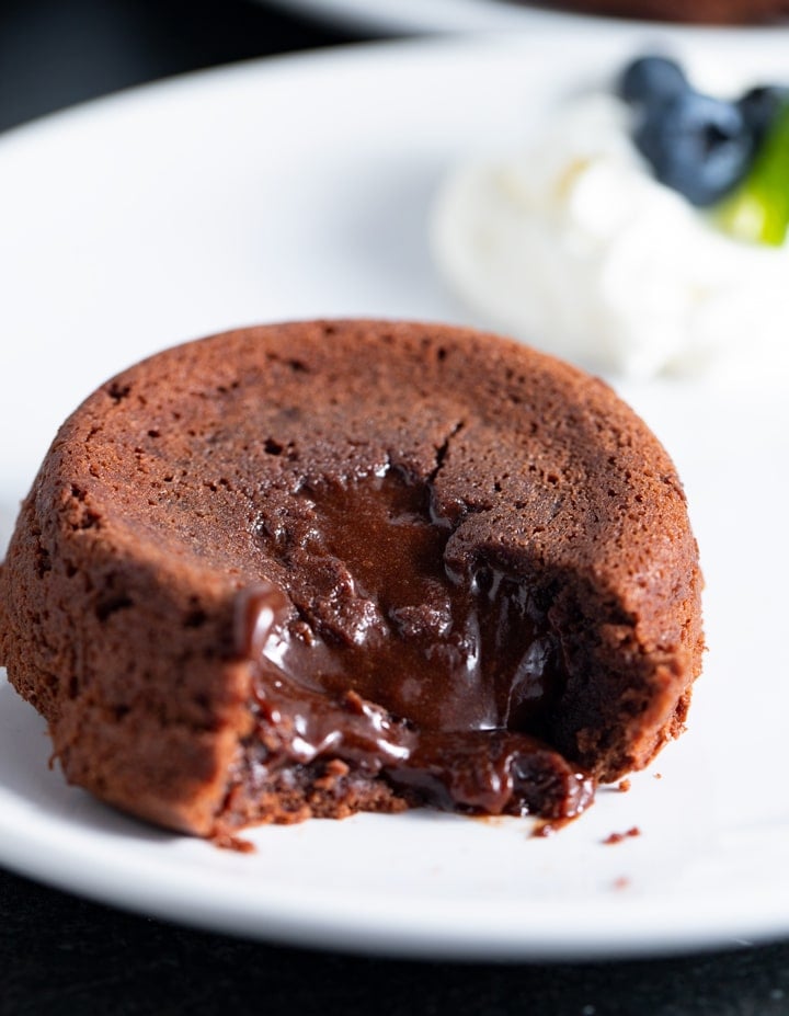 molten lava cake on white plate with whipped cream and blueberries in the  background