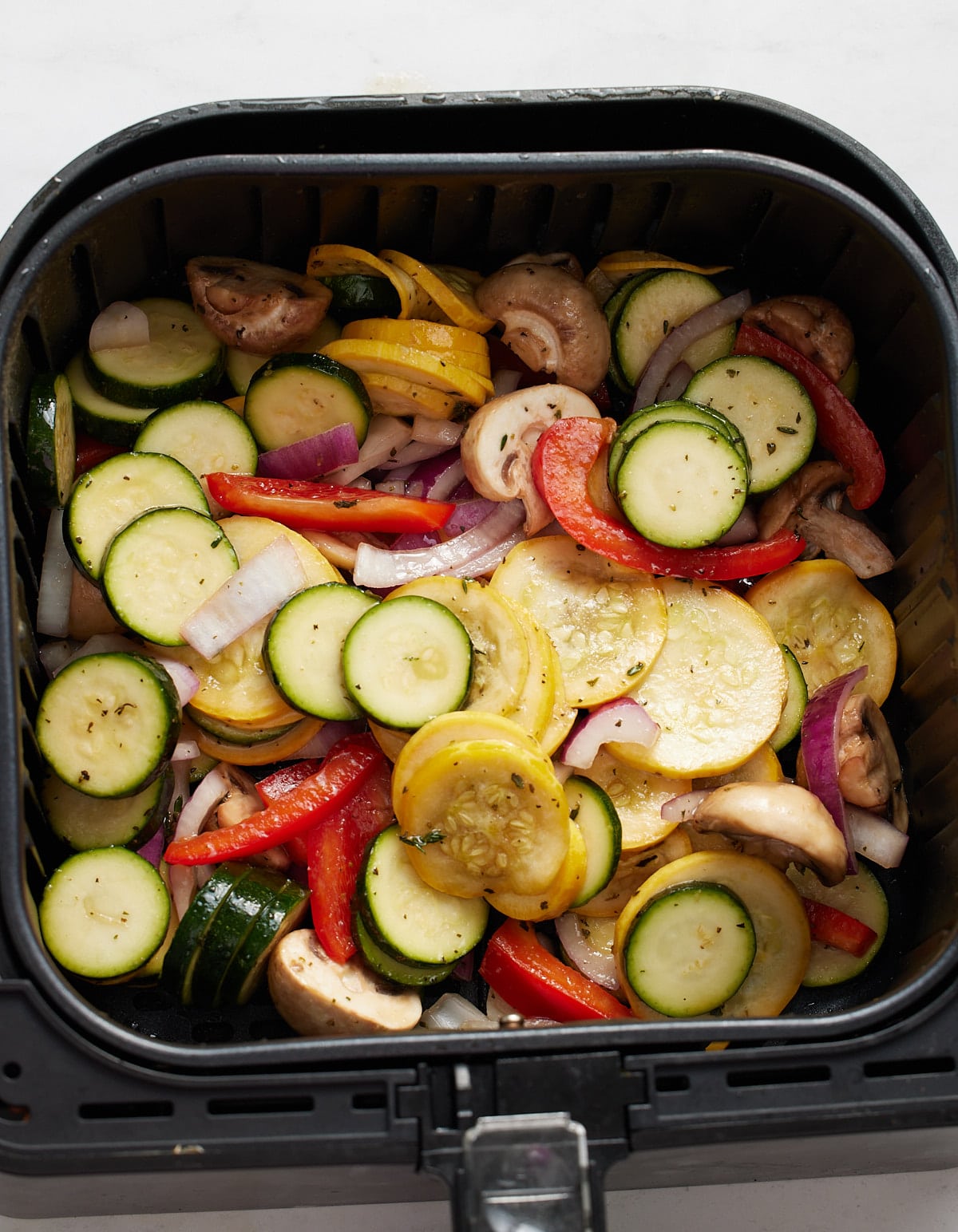 The uncooked vegetables in the air fryer basket