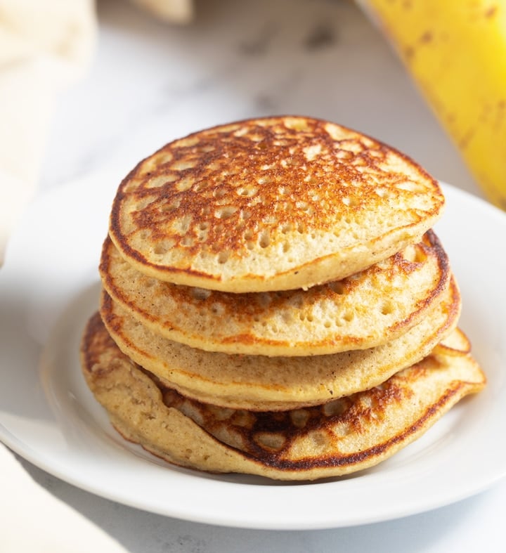 A stack of banana oatmeal pancakes on a white plate