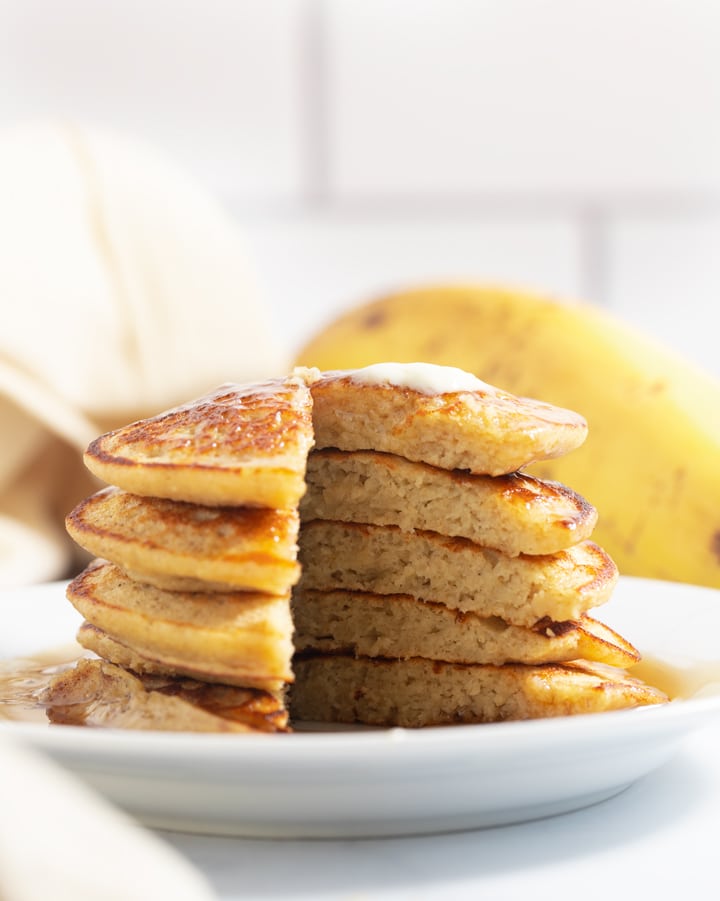 A stack of banana oatmeal pancakes with a slice taken out of them