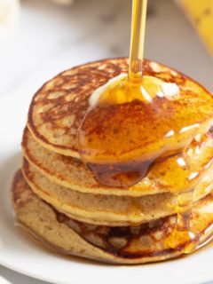 banana oatmeal pancakes with syrup being poured on top