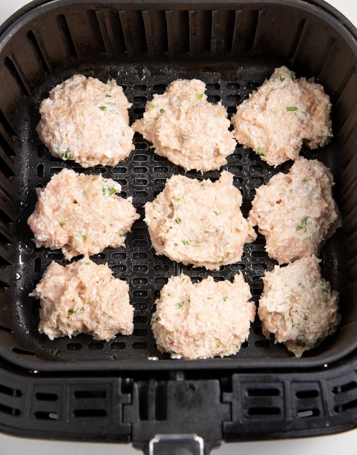 The uncooked chicken patties in the air fryer basket