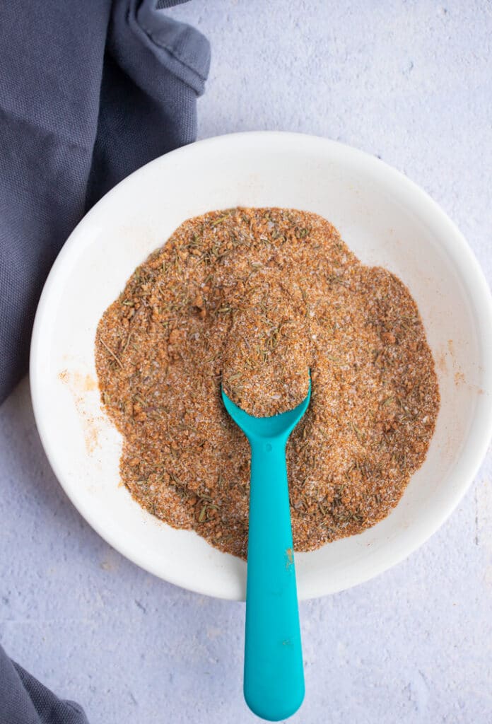 spices and herbs on white plate, mixed with spoon sticking in the middle