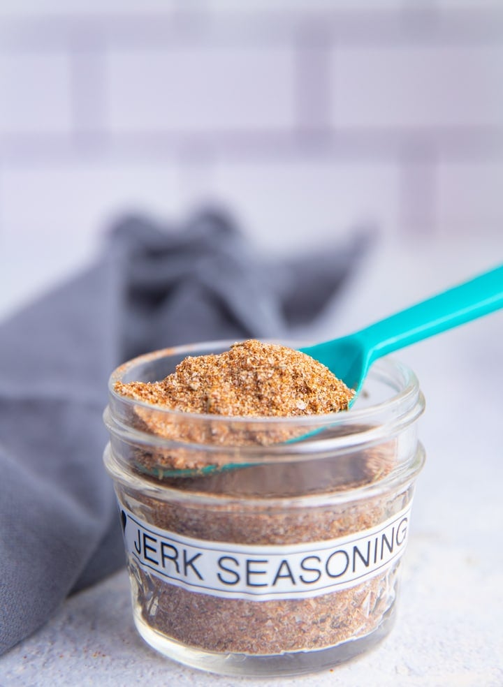 Jamaican Jerk Seasoning in a jar with label and spoon sticking out top