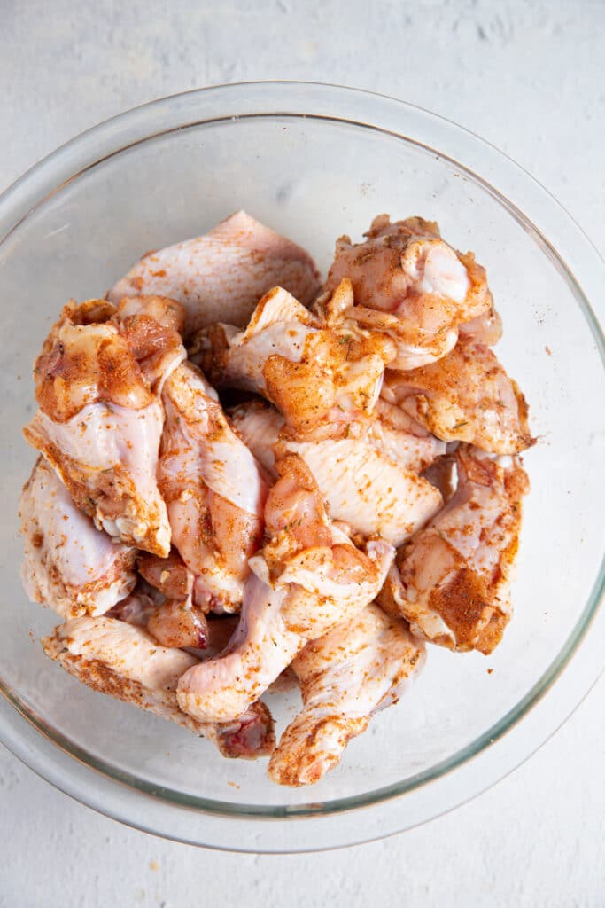 Chicken wings in a bowl with jerk seasoning