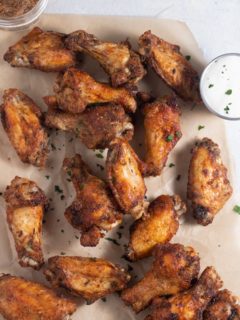 Jerk chicken wings on parchment served with a dip