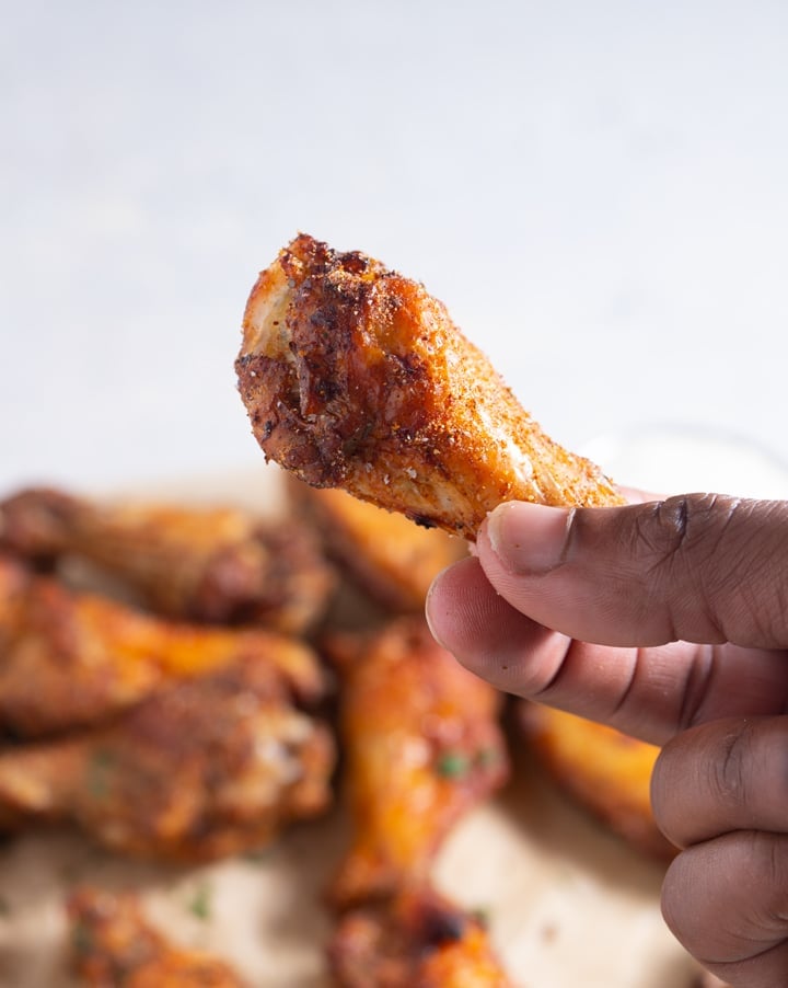 A jerk chicken wing being held towards camera