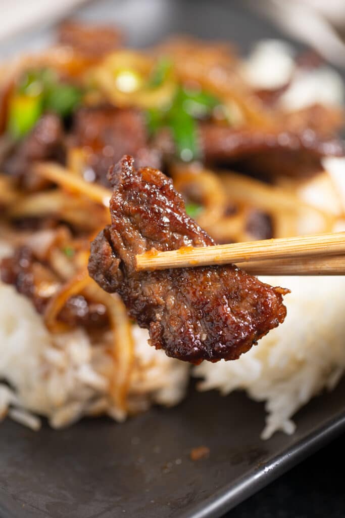 A piece of Mongolian beef held with chopsticks