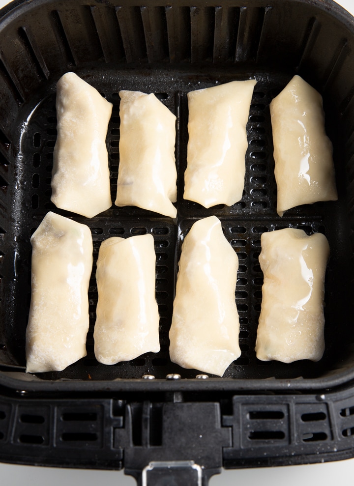 The egg rolls in the air fryer basket before being cooked