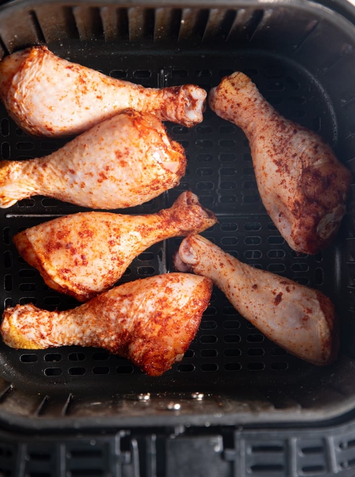 Seasoned chicken legs in the air fryer basket