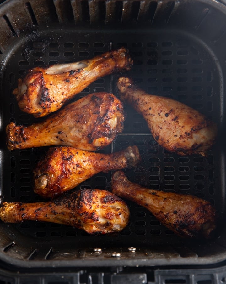 The cooked chicken legs in air fryer basket before being glazed