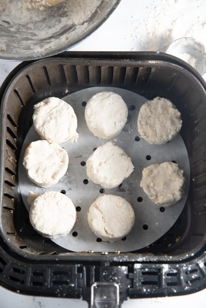 The uncooked biscuits in the air fryer basket