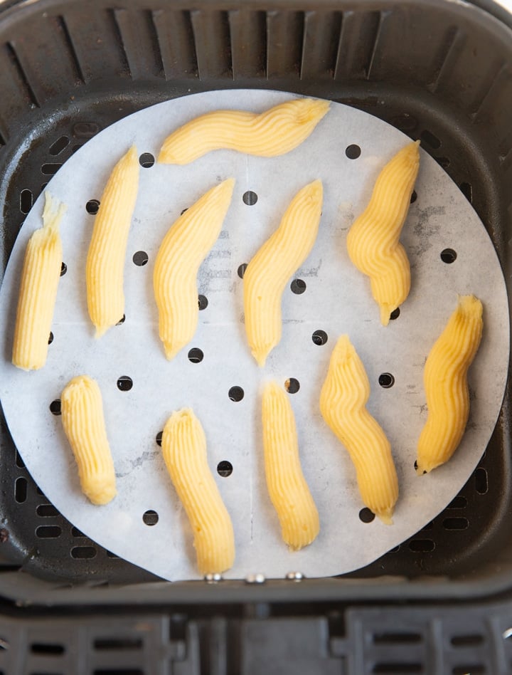 The piped churro dough in the air fryer basket