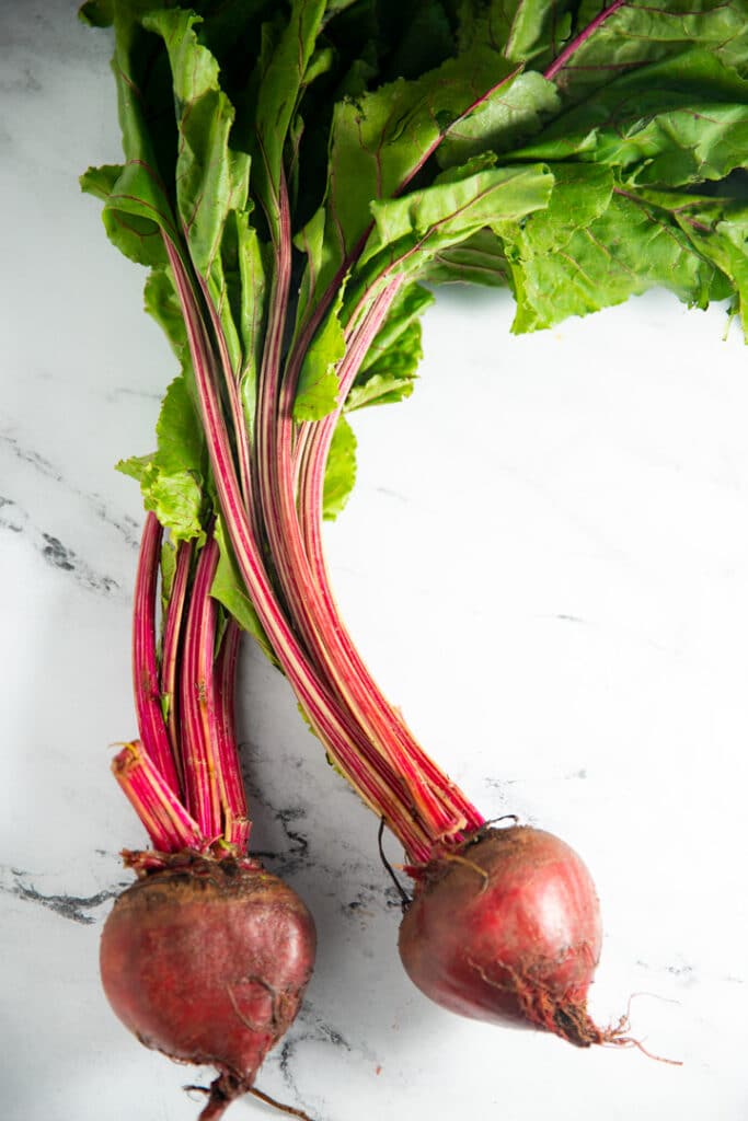 2 beets laying on marble background