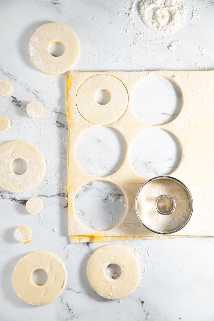 Cutting donut shapes in the dough with 2 different sized cookie cutters