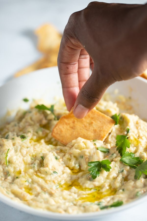 A chip being dipped into baba ghanoush