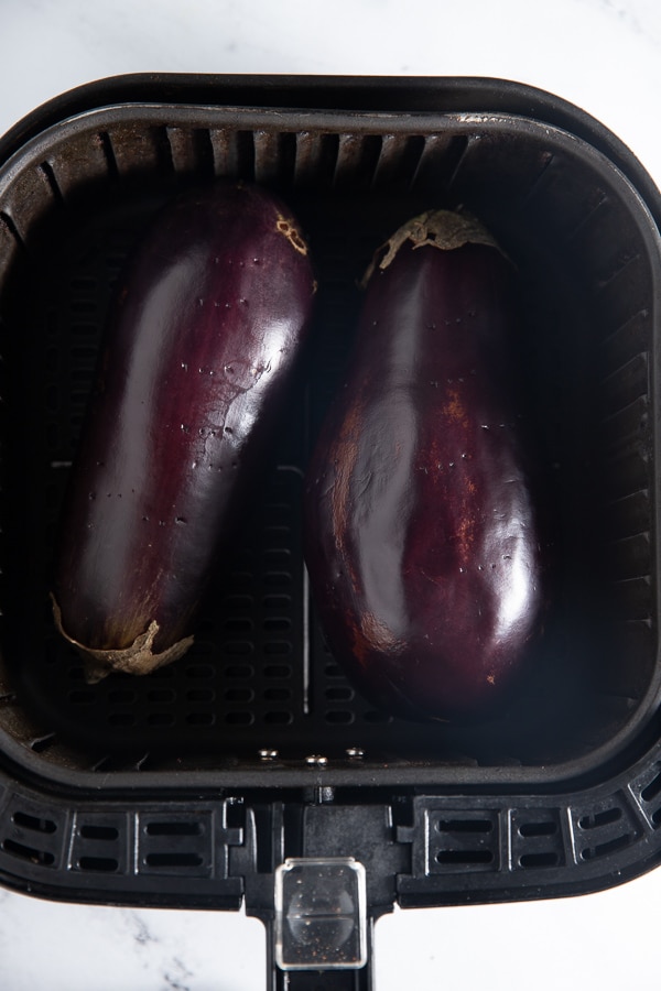 Two eggplants in the air fryer basket