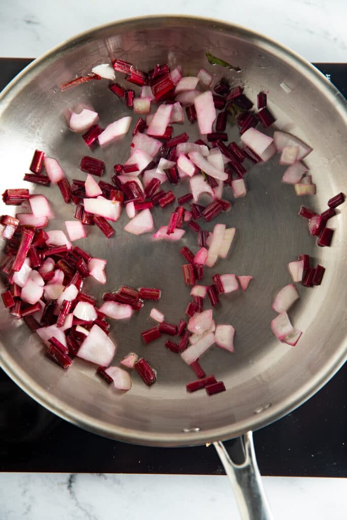 onions and beet stems cooking in a pan