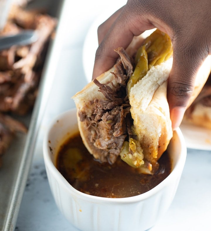 Italian beef in a sandwich being dipped in jus