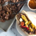 italian beef sandwich on plate next to shredded beef