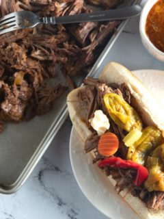 italian beef sandwich on plate next to shredded beef